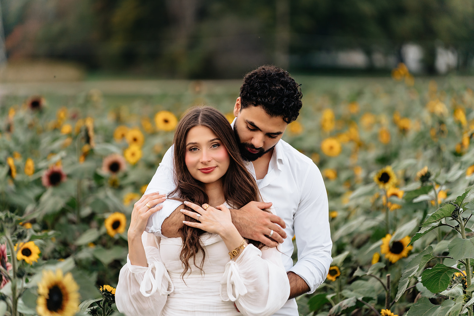 Suemaya laughing as Assad embraces her from behind among the sunflowers