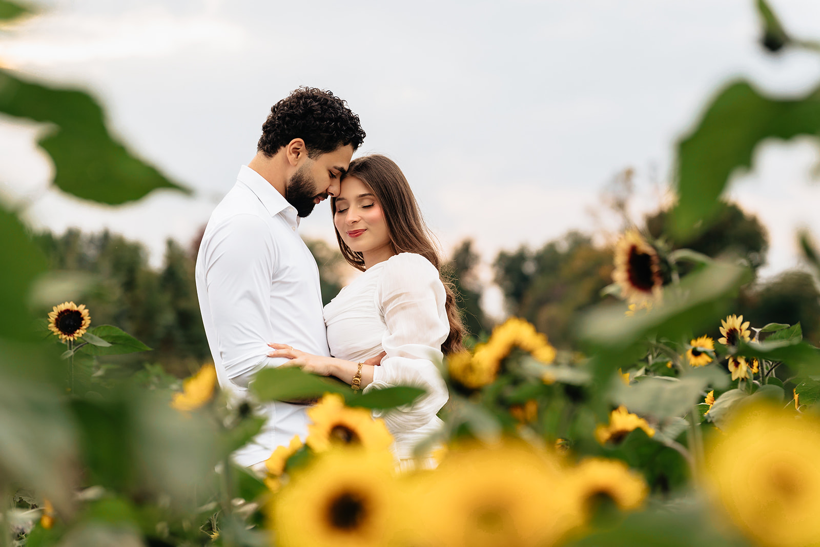 Suemaya and Assad standing close together among the sunflowers during their Rogish Farm love-story session