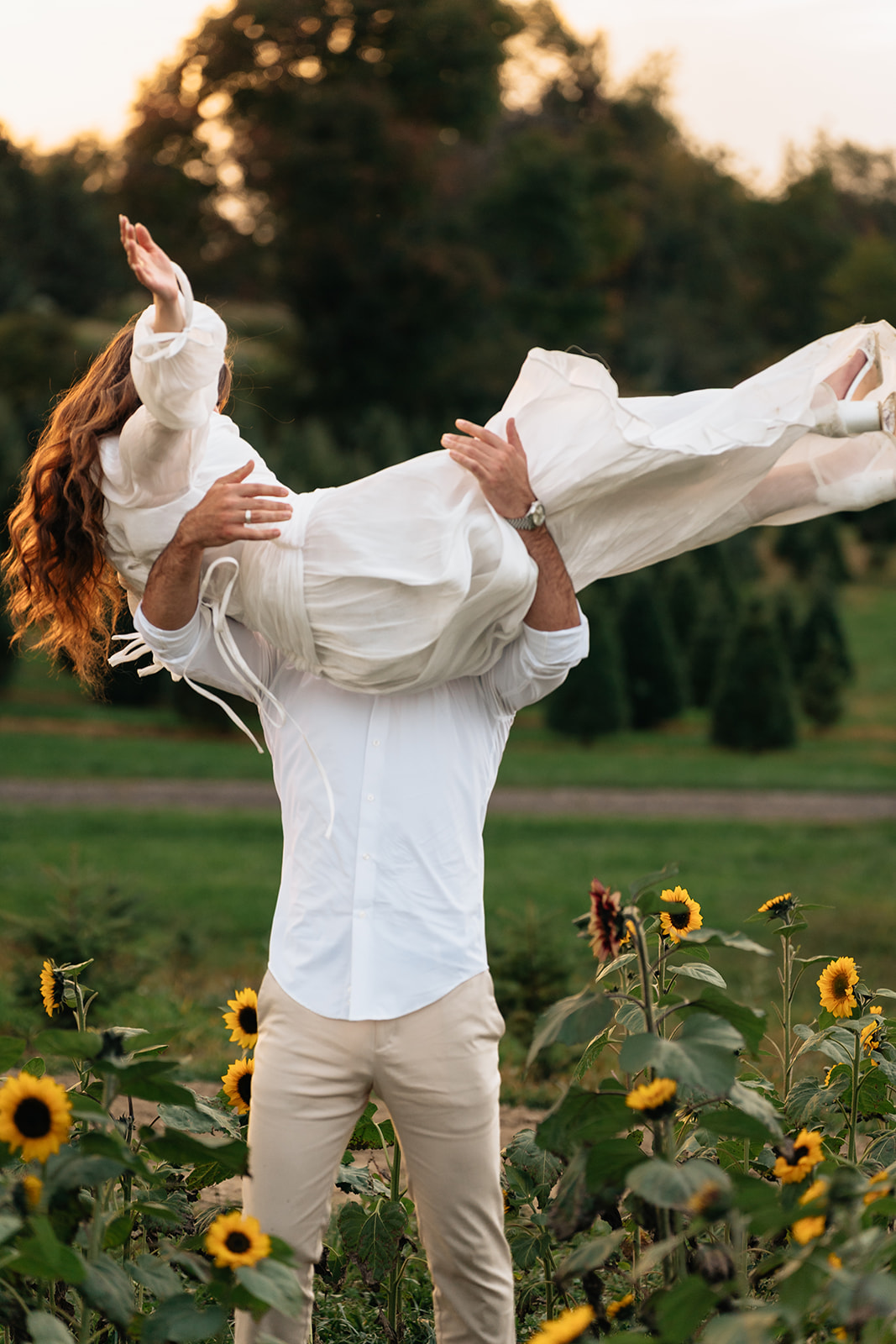 Assad carrying Suemaya across the sunflower field as her white skirt moves in the air