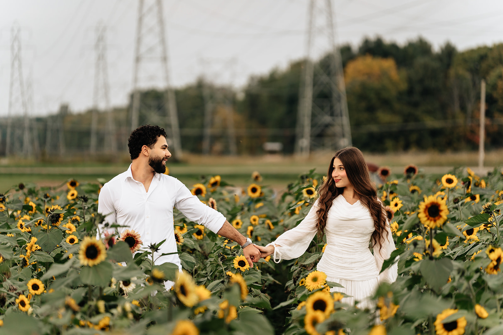 Suemaya and Assad running hand in hand through the sunflower rows at Rogish Farm